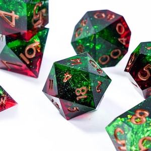 Puede incluir: Un conjunto de dados poliédricos en tonos verdes y rojos con números cobrizos. Los dados están hechos de resina transparente con purpurina y un efecto veteado. Para juegos de mesa.