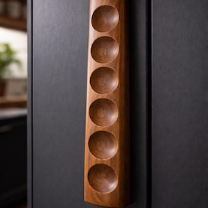 May include: A vertical, wooden wine rack with six circular indentations. The rack is made of a warm-toned wood and is mounted on a dark gray surface. The design is simple and elegant, suitable for storing wine bottles.