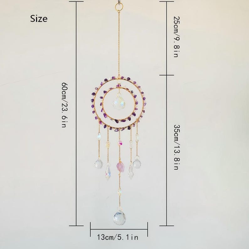 May include: A decorative suncatcher with a gold-colored metal frame and hanging crystals. The suncatcher features two concentric circles adorned with purple stones. The total length is 23.6 inches, with a width of 5.1 inches.