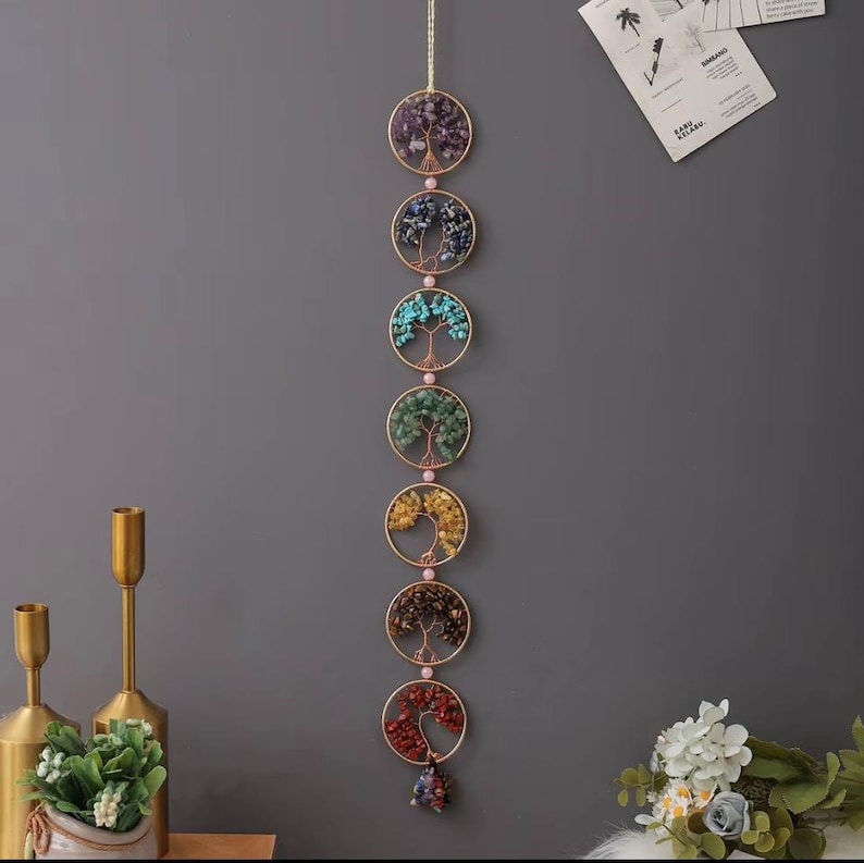 May include: A wall hanging featuring seven circular designs, each with a wire tree filled with colorful gemstones. The gemstones include purple, blue, turquoise, green, yellow, brown, and red. The circles are connected by a gold-colored chain.