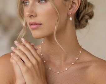 May include: A gold chain necklace and matching bracelet, each featuring evenly spaced small white pearls. The set includes a pair of gold drop earrings, each with a single white pearl. The jewelry is crafted with a delicate gold-tone metal chain.