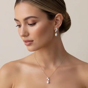 Puede incluir: Elegante conjunto de joyas con un delicado collar y pendientes a juego. El collar y los pendientes tienen un dise&ntilde;o de hojas con una perla en forma de l&aacute;grima. La joyer&iacute;a es dorada y est&aacute; engastada con cristales transparentes.