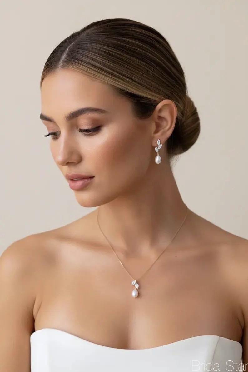 Puede incluir: Elegante conjunto de joyas con un delicado collar y pendientes a juego. El collar y los pendientes tienen un dise&ntilde;o de hojas con una perla en forma de l&aacute;grima. La joyer&iacute;a es dorada y est&aacute; engastada con cristales transparentes.