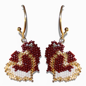 May include: A pair of heart-shaped earrings. The earrings are made of small, red, white, and gold beads. The earrings hang from gold-colored hoops.