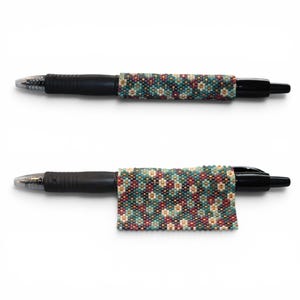 May include: Two black pens featuring a beaded wrap. The top pen has a cylindrical beaded sleeve, while the bottom pen features a flat, rectangular beaded panel. Both display a repeating geometric pattern in teal, cream, and dark red beads.
