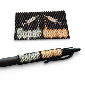 May include: A black pen with a beaded sleeve displaying the words "Super Nurse" in white, green, and orange beads. A matching beaded rectangle with syringes and the same text is also present.