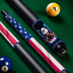 May include: Pool cues featuring American flag and bald eagle designs, with black leather grips. The image includes a nine ball and a two ball, set on a green felt surface. The cues are angled.