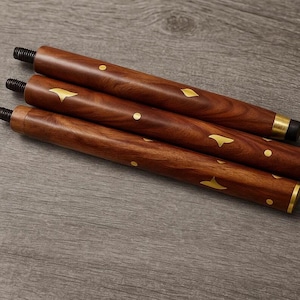 May include: Three wooden furniture legs with a rich brown finish. Each leg features gold-colored decorative accents in the shape of dots and stylized leaves. The legs have threaded ends for easy attachment. The legs are angled slightly, suggesting they are for a table or chair.