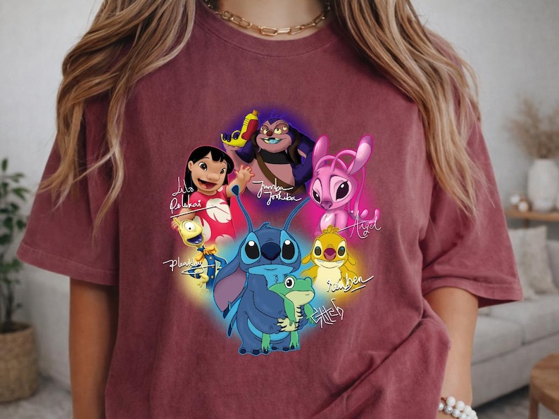 Op de afbeelding: Bordeauxkleurig T-shirt met een kleurrijke afbeelding van personages uit de animatiefilm Lilo & Stitch. Het ontwerp bevat Stitch, Lilo en andere personages, met hun namen in cursief geschreven. Het shirt is gemaakt van een zacht materiaal.
