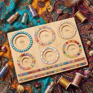 May include: A rectangular wooden bead board featuring six circular channels labeled 6in, 6.5in, 6.75in, 7in, 7.5in, and 8in, each containing a beaded bracelet. The board includes two straight channels with rulers and alphabet beads, surrounded by glass bead vials.