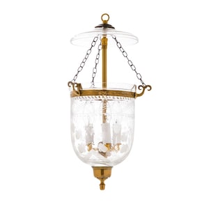 May include: A clear glass hanging lantern with etched floral designs and brass accents. The lantern has a round top and bottom, with a decorative brass band around the middle. It hangs from a chain.
