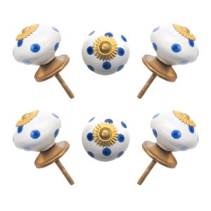 May include: Six white ceramic cabinet knobs with blue polka dots and gold-colored metal hardware. The knobs have a decorative gold-colored sunburst design on the top. The knobs are arranged on a white background.