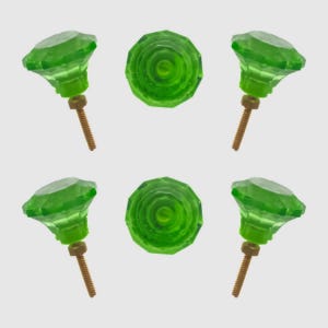 May include: Six green glass cabinet knobs. The knobs have a faceted, gem-like appearance with a brass screw. Two knobs are shown from the top, revealing a spiral design. The other four knobs are shown from the side.