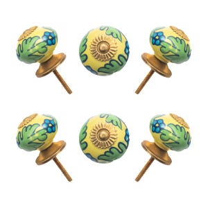 May include: Six decorative cabinet knobs with a yellow base, adorned with green leaves and blue floral accents. Each knob has a brass-colored base and screw for easy installation. The knobs are a charming addition to any furniture piece.