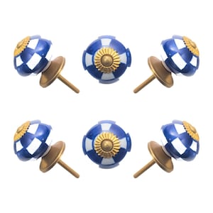 May include: Six decorative cabinet knobs. Each knob features a blue and white checkered pattern with a gold-colored floral design in the center. The knobs have a brass-colored base and screw.