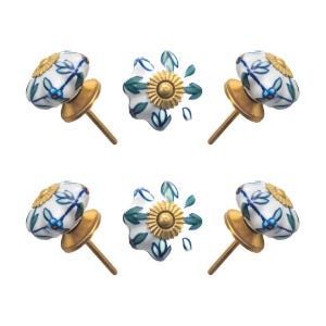 May include: Set of six decorative ceramic cabinet knobs. Each knob features a white base with blue and green floral designs, a gold-colored metal base, and a screw for installation. The knobs have a unique, handcrafted appearance.