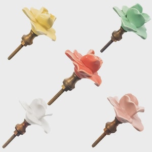 May include: Five ceramic flower-shaped cabinet knobs in various colors: yellow, green, coral, white, and pink. Each knob has a brass-colored base and a threaded screw for installation. These decorative knobs add a floral touch to furniture.