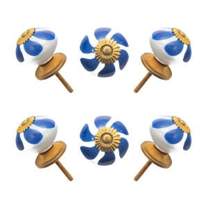May include: Six decorative cabinet knobs. Each knob features a white and blue floral design with a gold-colored metal base and screw. The knobs are arranged against a white background. The knobs are a decorative hardware item.