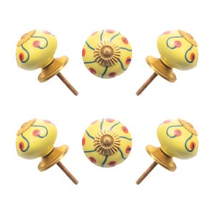 May include: Six yellow cabinet knobs with decorative floral patterns. Each knob features a brass base and screw, with a design of red dots and blue swirls on the yellow surface. The knobs are for furniture hardware.