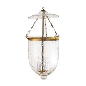 May include: Clear glass pendant light with a gold-colored metal trim and chain. The glass shade is etched with a star pattern. The light fixture has four candelabra-style bulbs.