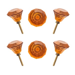 May include: Six amber-colored cabinet knobs with faceted, gem-like tops. The knobs have a brass-colored screw base. Two knobs are shown from above, and four are shown from the side.