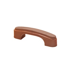 May include: A brown cabinet pull with a curved handle. The handle is a lighter shade of brown on top and has a rectangular base with rounded edges. The pull is made of a solid material and is designed for easy gripping.