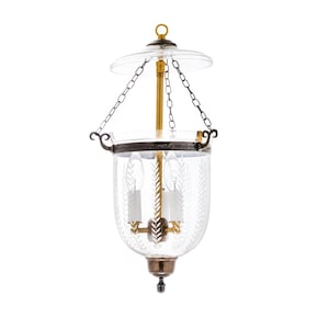 May include: A clear glass hanging lantern with a decorative etched leaf pattern. The lantern has a brass-colored central support and a metal frame. It is suspended by a chain and features a clear glass top and bottom.