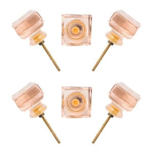 May include: Five decorative cabinet knobs. The knobs have a faceted, light pink glass design with a brass screw. Two knobs are square, and three are faceted with a round base.
