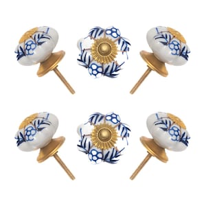 May include: Six decorative cabinet knobs. The knobs have a white background with blue floral designs and gold-colored metal bases. The knobs are arranged in a circular pattern against a white background.