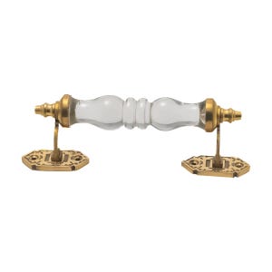 May include: A clear glass door pull with brass-colored hardware. The handle is cylindrical with a series of rounded sections. The mounting plates are hexagonal with decorative detailing. A classic design for cabinets or doors.