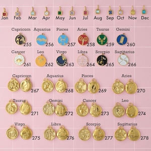 A zodiac and birthstone collection of gold plated stainless steel charms. Charms include birthstones, color zodiac signs, and gold zodiac sign charms. Charms are laid out on a pink background with identifying numbers.