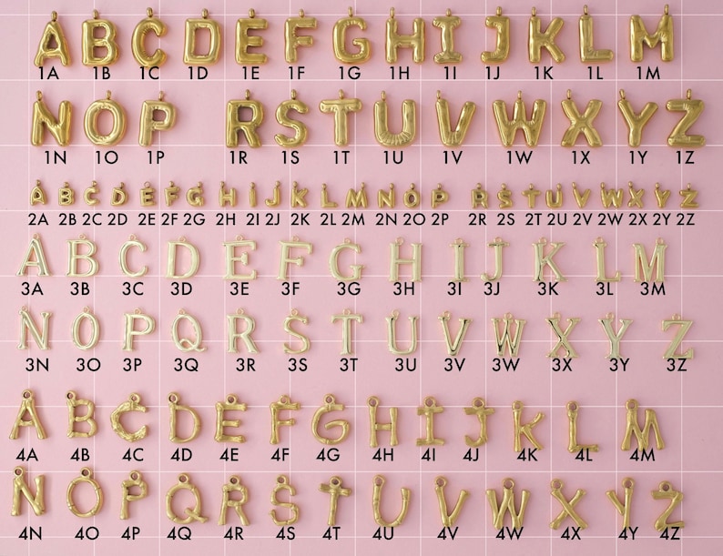 An initial letter collection of gold plated stainless steel charms. Charms include four different styles of initial letters. Styles include big bubble letters, small bubbles, plain, and bamboo letters. Charms are laid out on a pink background with identifying numbers.
