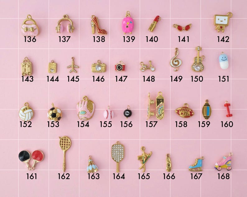 A collection of gold plated stainless steel charms. Charms include purse, headphones, high heels, luggage, travel theme, music instruments, and sports theme like football and pickleball. Charms are laid out on a pink background with identifying numbers.