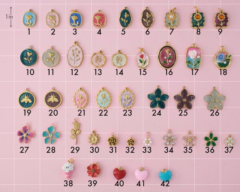 A collection of gold plated stainless steel charms. Charms include flowers, bees, and hearts. Charms are laid out on a pink background with identifying numbers.