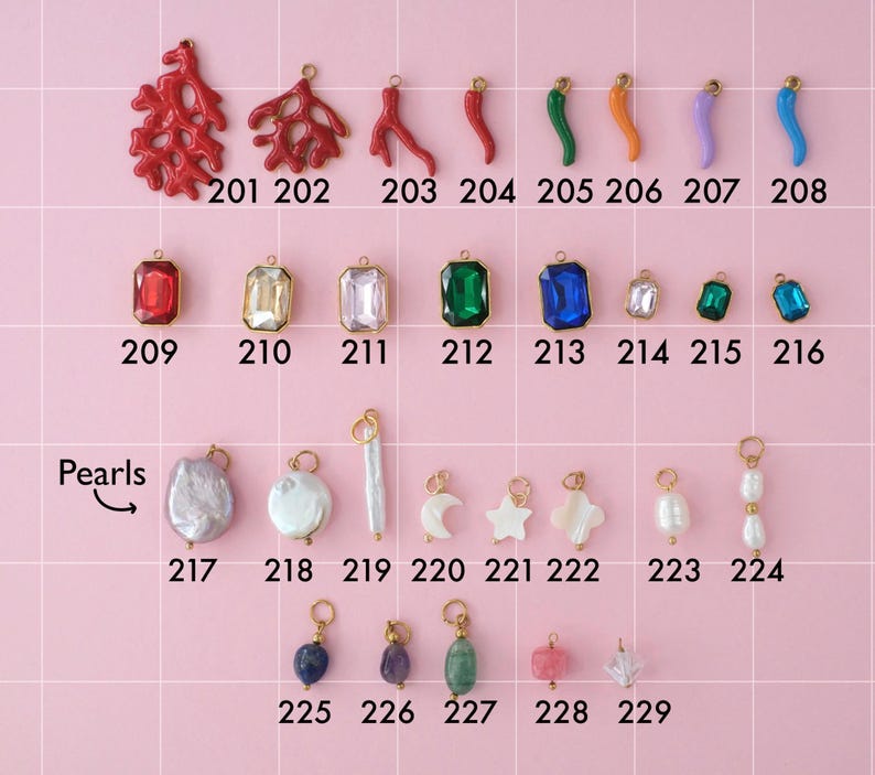 A collection of gold plated stainless steel charms. Charms include hot peppers, gemstones, and pearls. Charms are laid out on a pink background with identifying numbers.