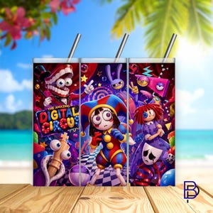 Puede incluir: Tres vasos con pajitas de acero inoxidable presentan ilustraciones coloridas de "The Amazing Digital Circus". Los diseños incluyen un bufón, un personaje con dientes con sombrero de copa y una muñeca triste. Los vasos están sobre un fondo de playa.