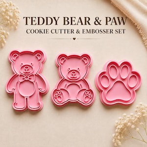 Puede incluir: Un juego de tres cortadores de galletas y estampadores rosas que incluye un oso de peluche de pie con pajarita, un oso de peluche sentado y una huella de pata. El texto TEDDY BEAR & PAW COOKIE CUTTER & EMBOSSER SET aparece sobre los objetos.