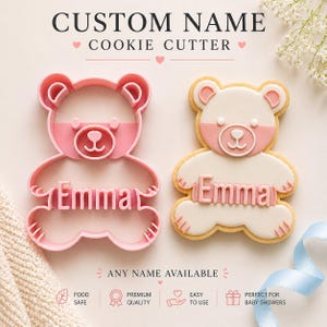 Pode incluir: Um cortador de biscoitos em forma de urso de pelúcia rosa e um biscoito decorado. O cortador de biscoitos tem a forma de um urso com o nome "Emma" recortado. O biscoito decorado é branco com detalhes em rosa e o nome "Emma". O texto "Custom Name Cookie Cutter" está no topo.