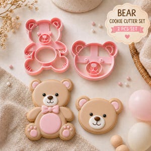 Può includere: Un set di formine per biscotti a forma di orso rosa e due biscotti orso decorati. I biscotti sono marroni con dettagli rosa, tra cui un papillon e la pancia. Il testo "BEAR COOKIE CUTTER SET 2 PCS SET" è visualizzato su un'etichetta decorativa.
