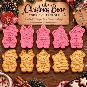 May include: A set of five pink plastic cookie cutters and five corresponding bear-shaped cookies. The set includes designs of bears with a gift, antlers, a winter hat, a Christmas tree, and a Santa hat. Text reads Christmas Bear COOKIE CUTTER SET.