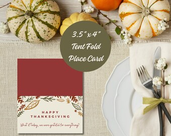 May include: A 3.5" x 4" tent fold place card with a burgundy background and a white border. The card features a fall-themed design with leaves and the text "Happy Thanksgiving. What if today, we were grateful for everything?"