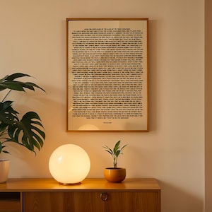 Pode incluir: Uma peça de arte de parede retangular emoldurada com um fundo bege e texto impresso em preto denso. A impressão contém vários parágrafos de conteúdo escrito em uma fonte sem serifa, exibida em uma moldura de madeira na parede.