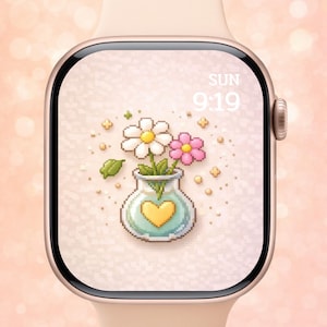 Könnte beinhalten: Eine goldene Apple Watch zeigt ein Blumendesign. Das Zifferblatt zeigt eine pixelige Vase mit einem gelben Herzen, die weiße und rosa Blumen enthält. Die Uhrzeit ist 9:19 Uhr am Sonntag. Die Uhr hat ein hellrosa Armband.