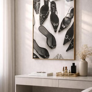 Puede incluir: Impresi&oacute;n en blanco y negro enmarcada con varios zapatos de tac&oacute;n alto. Los zapatos incluyen zapatos de sal&oacute;n, sandalias y slingbacks, algunos con adornos. La impresi&oacute;n se muestra sobre una c&oacute;moda con una bandeja dorada que contiene frascos de perfume y un jarr&oacute;n con flores secas.