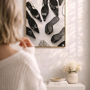 Puede incluir: Una impresi&oacute;n enmarcada que presenta una variedad de zapatos de mujer, incluyendo tacones altos y sandalias, en varios estilos y colores. Los zapatos est&aacute;n dispuestos sobre un fondo blanco, con un marco dorado. La impresi&oacute;n se exhibe en una pared.