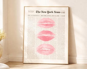 Puede incluir: Una impresión enmarcada con un fondo de periódico y tres huellas de labios rosas. La parte superior de la impresión dice "The New York News" e incluye la fecha "22 de julio de 2028". La impresión está en un marco dorado.