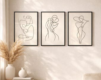 Puede incluir: Tres impresiones artísticas enmarcadas con dibujos lineales minimalistas de figuras humanas en negro sobre un fondo crema. La obra de arte se exhibe en una pared blanca, con una mesa auxiliar de madera y un jarrón decorativo en primer plano.