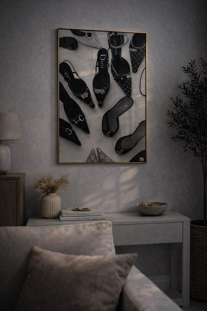 Puede incluir: Una obra de arte enmarcada que presenta una colecci&oacute;n de zapatos de tac&oacute;n negros y blancos. Los zapatos, incluyendo stilettos y sandalias, est&aacute;n dispuestos en una composici&oacute;n elegante. La obra se exhibe en un espacio con tonos neutros.