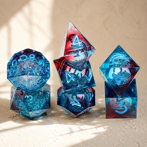 Può includere: Un set di dadi poliedrici trasparenti, blu e rossi, riempiti di glitter. Includono un dado a 20 facce e forme piramidali, con numeri blu. Ideale per giochi di ruolo.