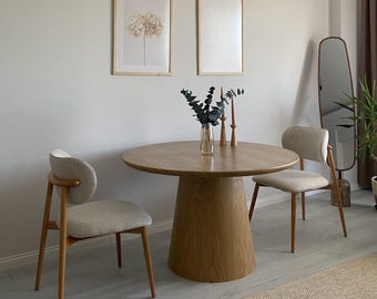 Mesa de comedor redonda de madera maciza con tapa de mármol y base de pedestal negra. Mueble contemporáneo a medida.